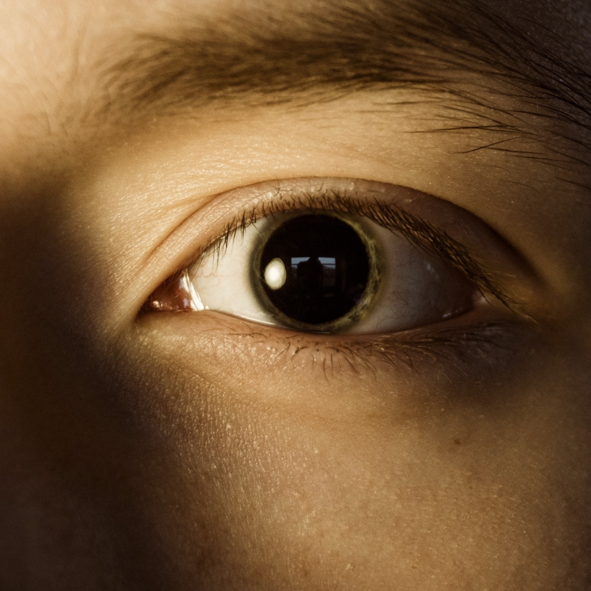 Close-up of a human eye with intense light reflecting off the pupil.