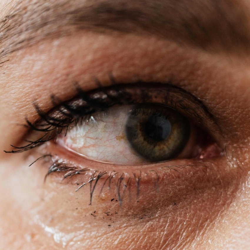 Close-up of a human eye with smudged black mascara on the eyelashes and lower eyelid.