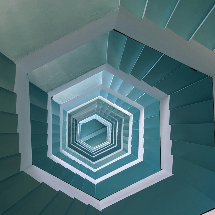 Green and white hexagonal staircase viewed from below with a spiraling pattern.