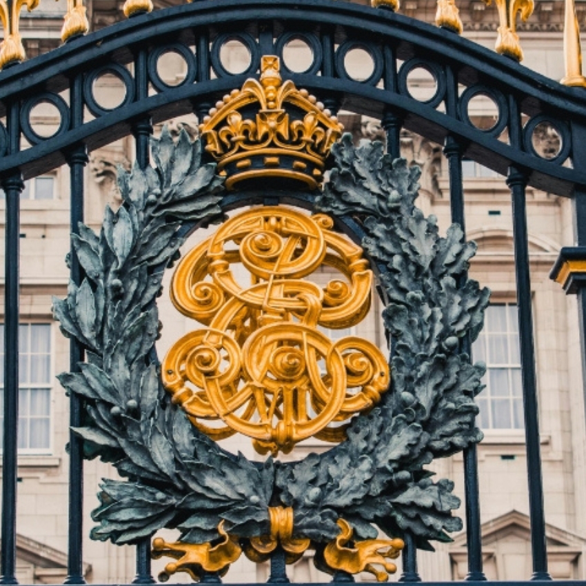 Royal crest with intertwined initials "ER" in gold, topped by a crown and laurel wreath, on a black gate.