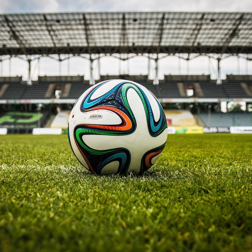 Colorful soccer ball on a grassy field in a stadium.