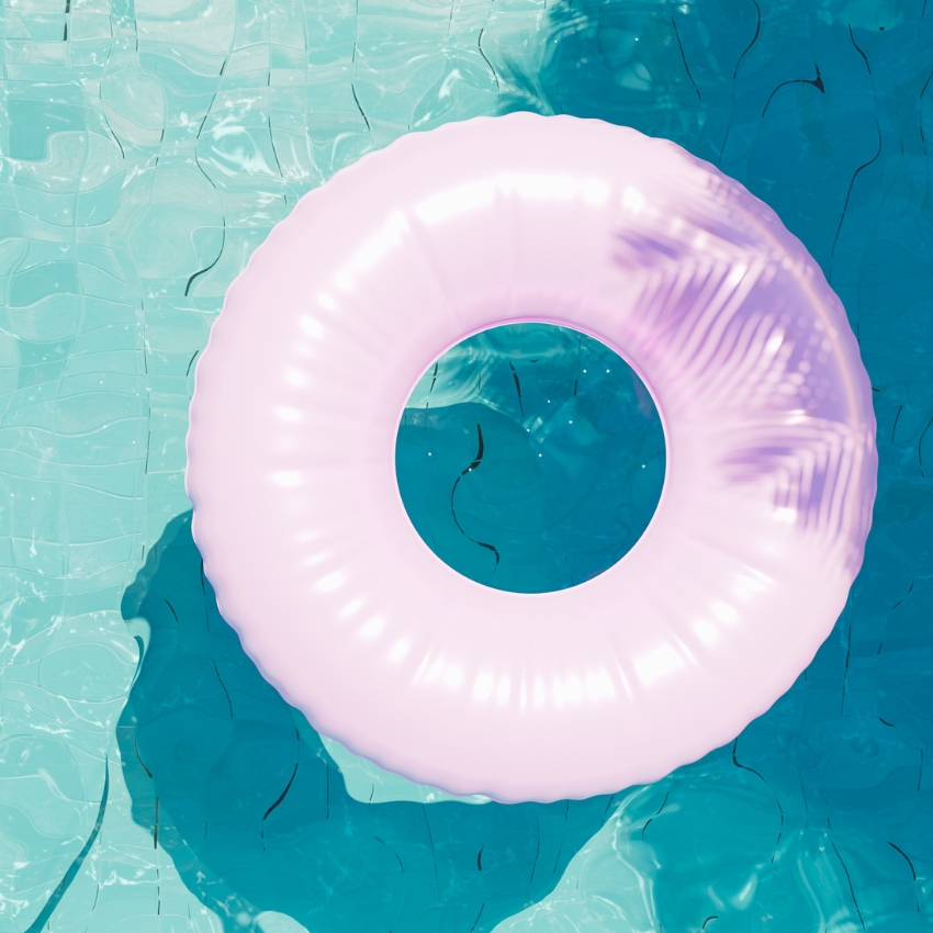 Pink inflatable pool ring floating on blue water.