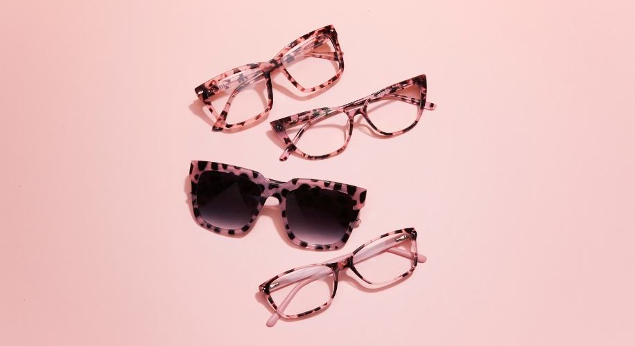 Four pairs of eyeglasses with pink and black tortoiseshell frames on a pink background.