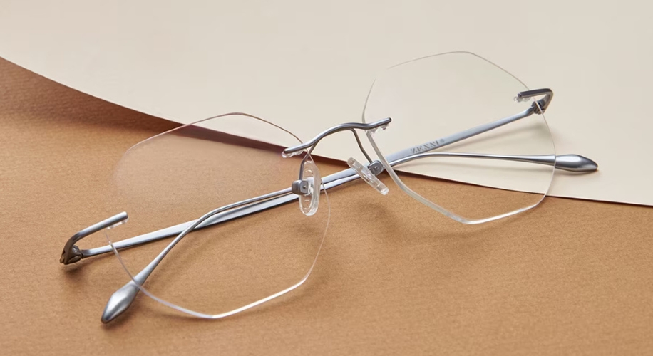 Rimless eyeglasses with silver metal temples on a beige surface.