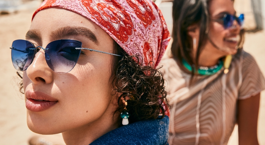 Woman wearing gradient blue sunglasses and a red patterned bandana.