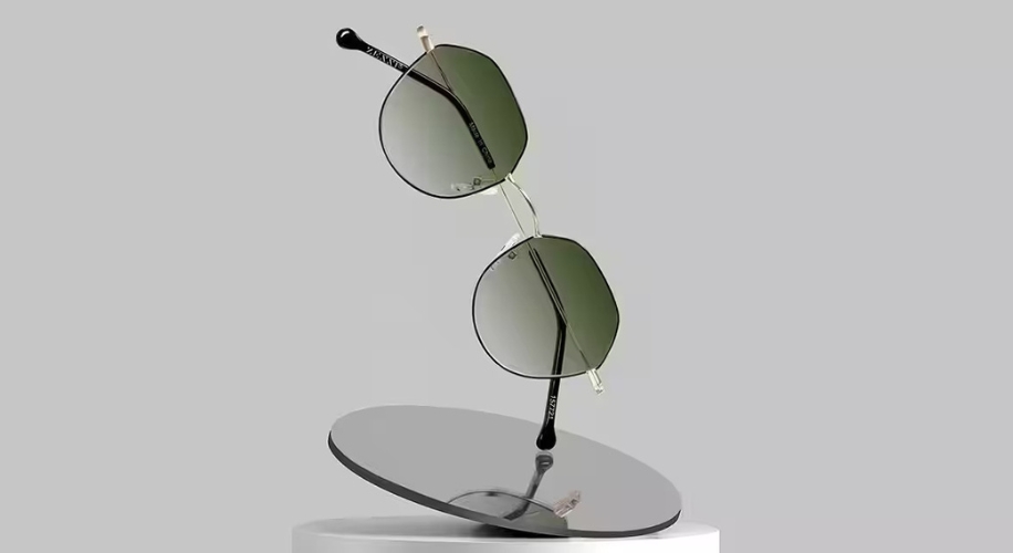 Round green-tinted sunglasses with thin metal frames displayed on a grey reflective surface.