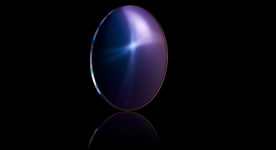 Purple-blue reflective optical lens on a black background.