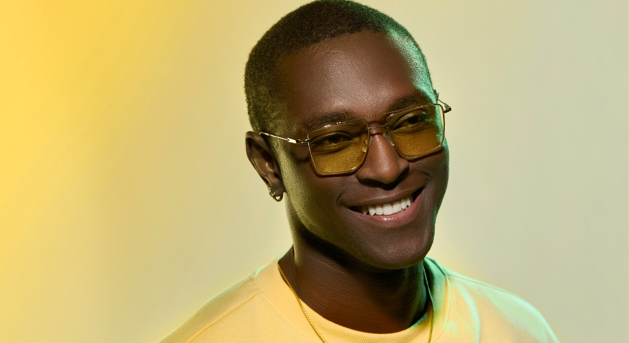 Man wearing yellow-tinted sunglasses and a yellow shirt, smiling.