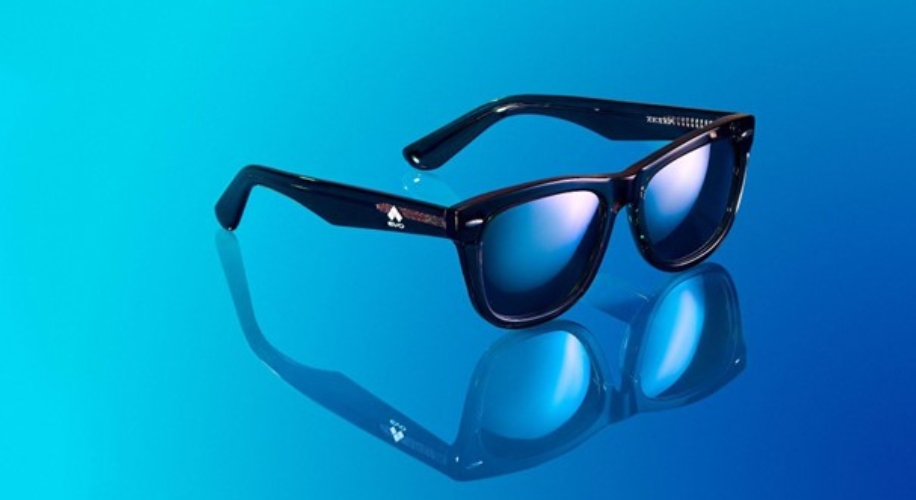 Black-framed sunglasses with blue mirrored lenses reflecting beneath them on a blue gradient background.