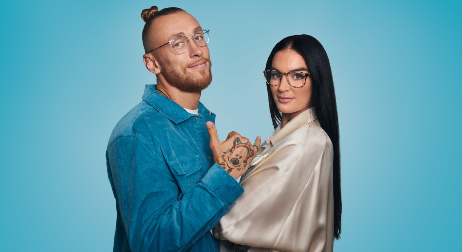 Two people wearing eyeglasses, one in a blue shirt with tattoos, the other in a white shirt with long black hair.