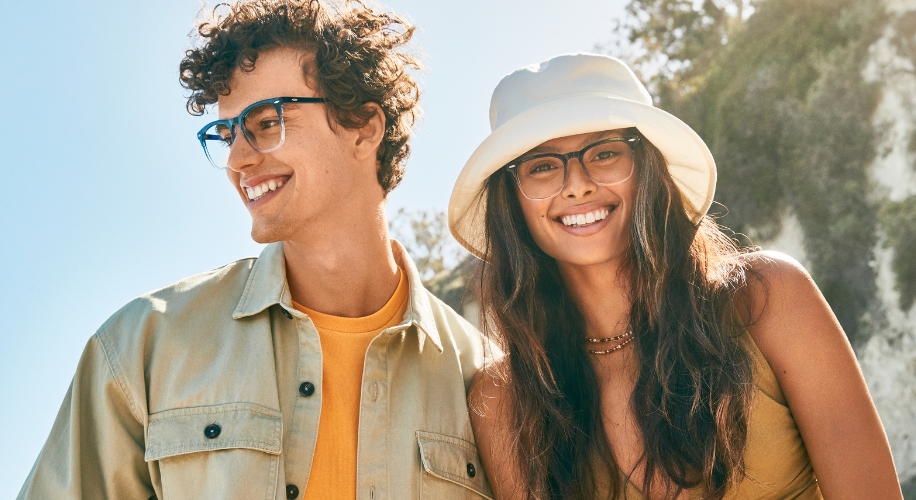 Two people wearing stylish eyeglasses, one in a light shirt, the other in a white hat and yellow top.