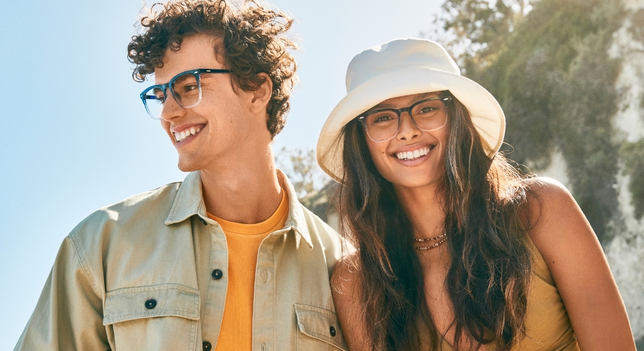 Two people wearing stylish eyewear; one with blue-framed glasses and the other with clear-framed glasses.