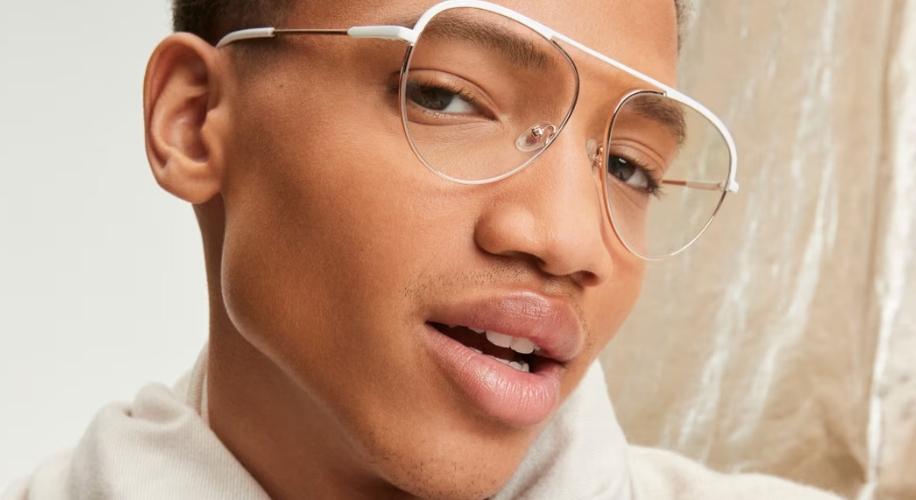 Close-up of a person wearing silver aviator-style glasses with clear lenses.