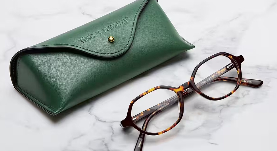 Tortoiseshell glasses with green leather case. Text on case: &quot;Timo x Warner&quot;. Text on glasses: &quot;Timo x Warner&quot;.