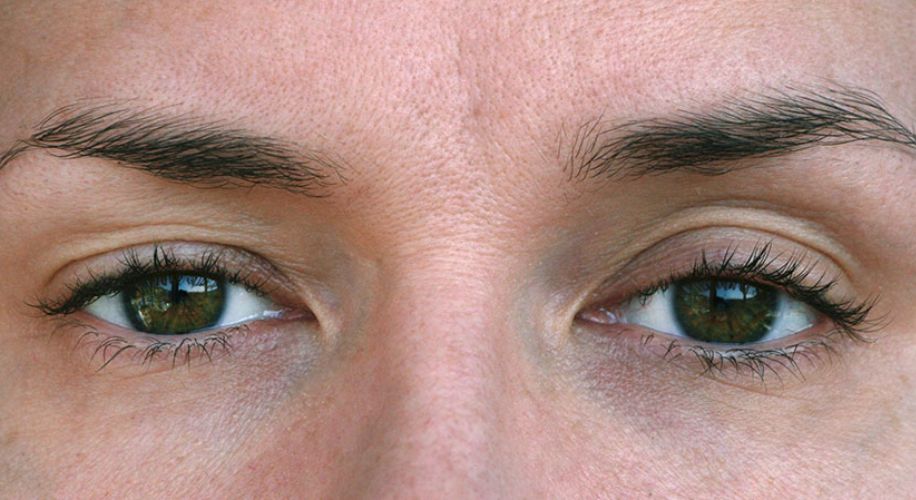 Close-up of green and brown eyes with natural eyebrows.