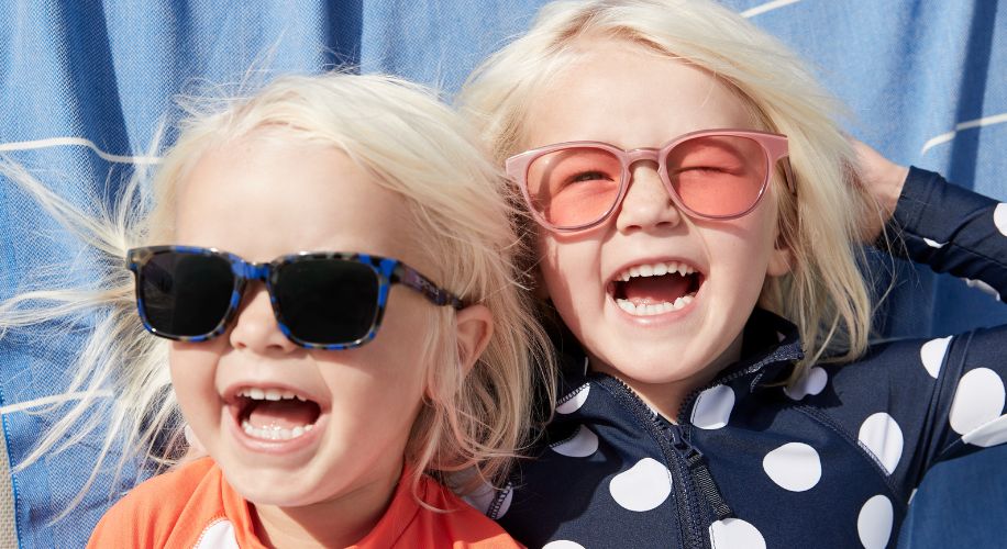 Two smiling children wearing brightly colored sunglasses.