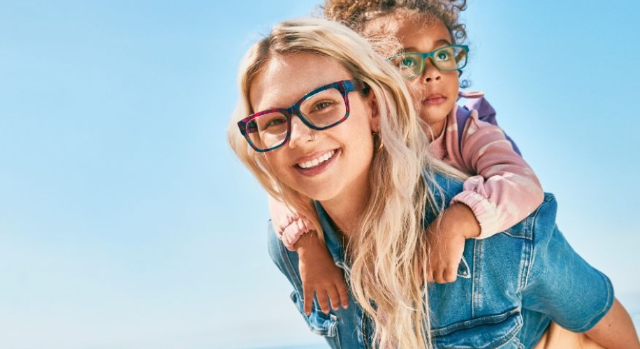 Two people wearing colorful eyeglasses; adult in rainbow frames and child in green frames.