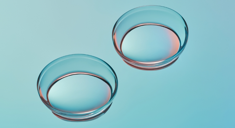 Two transparent contact lenses on a light blue background.