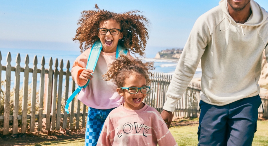 Two children wearing green glasses, the younger in a pink sweatshirt with the word &quot;LOVE&quot; printed on it.