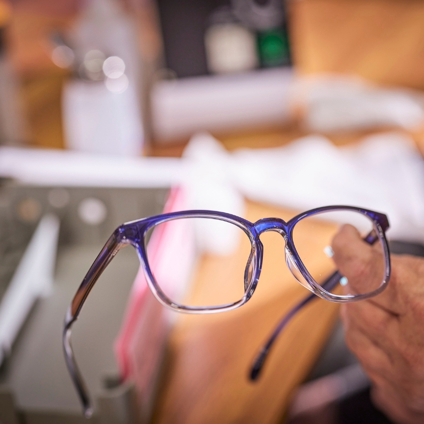 Blue eyeglasses frame held by a hand.