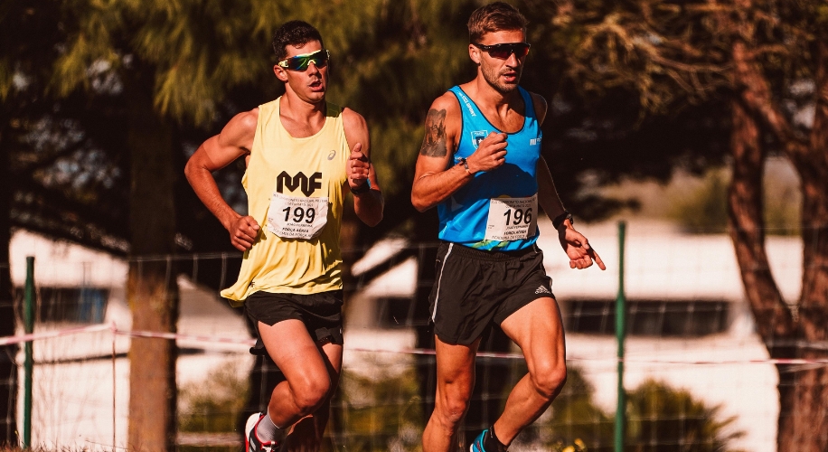 Two men running, wearing sports bibs numbered 196 and 199. Both in athletic gear with sunglasses.