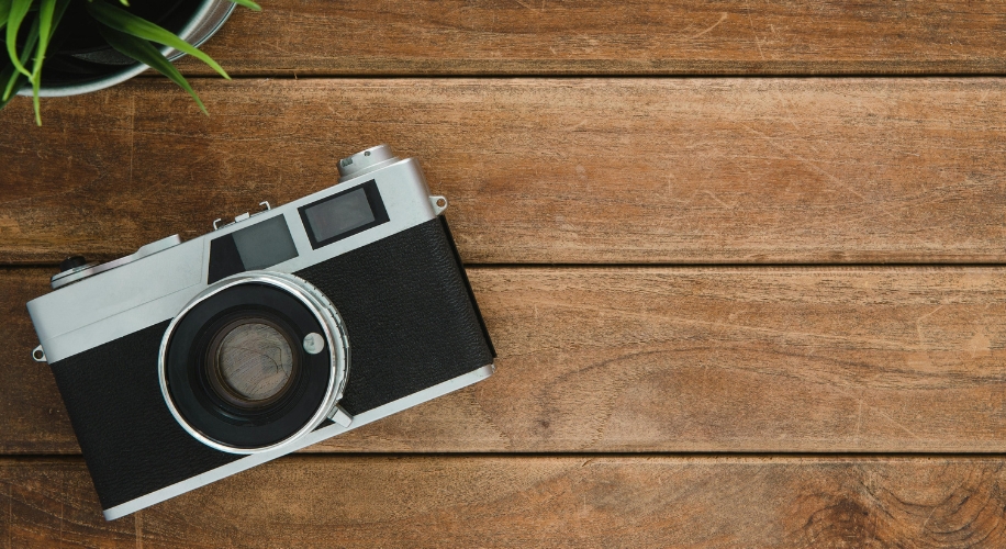 Vintage-style camera with a black body and silver accents placed on a wooden surface.