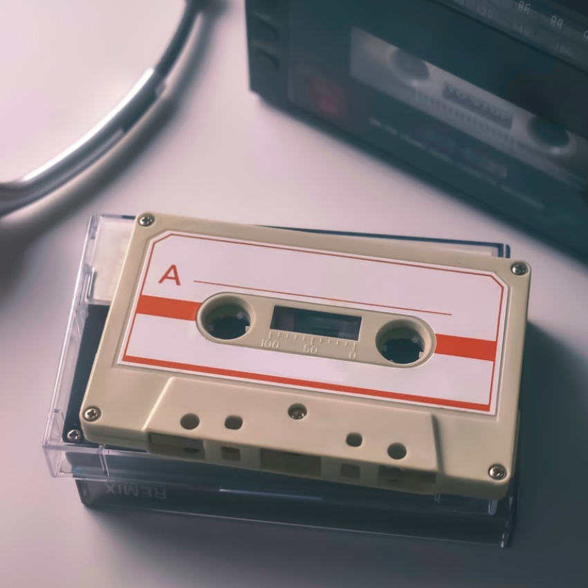 Beige audio cassette labeled "A" placed on a transparent plastic case.