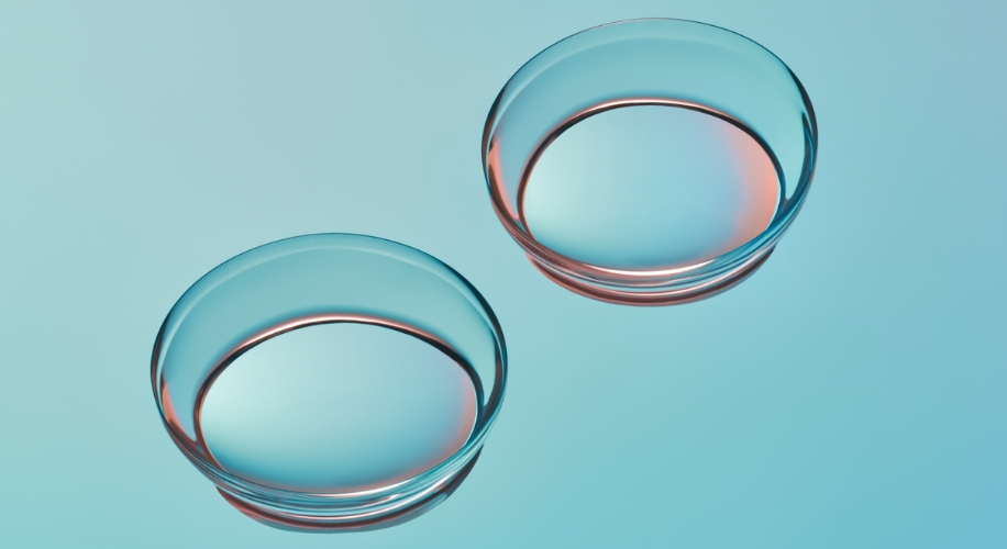 Two clear contact lenses on a gradient blue background.