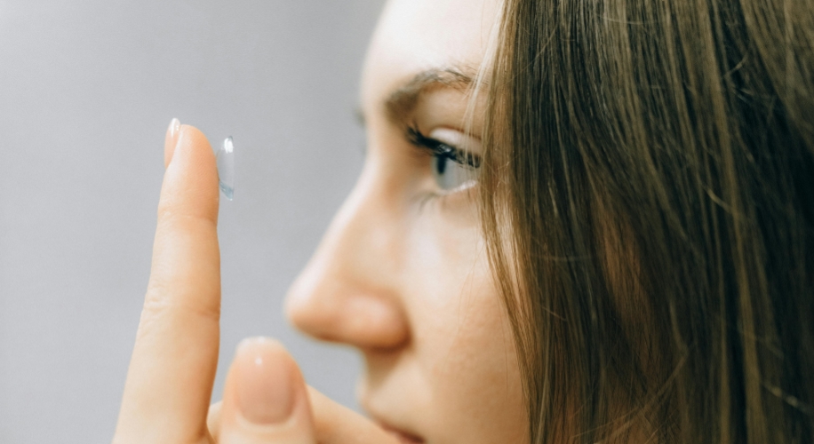 A person holding a contact lens on their finger, ready to insert it into their eye.