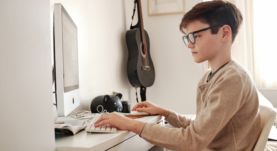 Boy using a desktop computer with a keyboard and mouse.