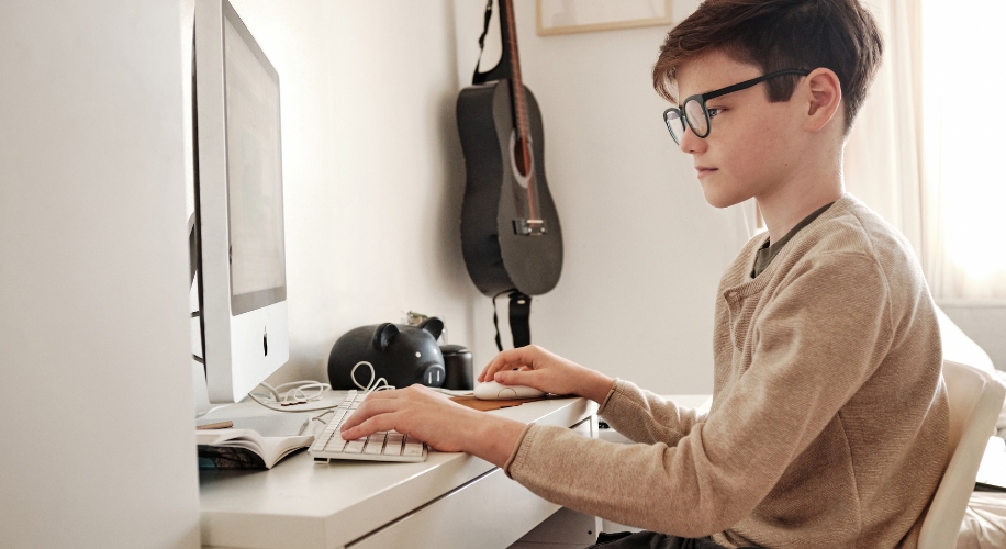 Child using a desktop computer with a large monitor and keyboard.