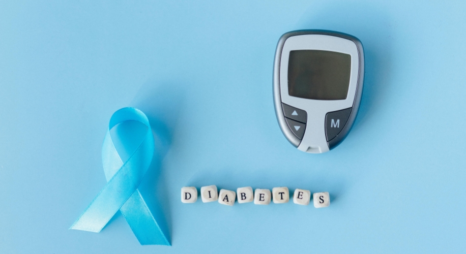 Blue ribbon, glucose meter, and lettered cubes spelling &quot;DIABETES&quot; on a light blue background.