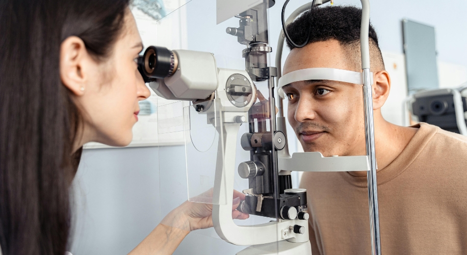 Optometrist performs an eye exam using a slit lamp biomicroscope on a patient.