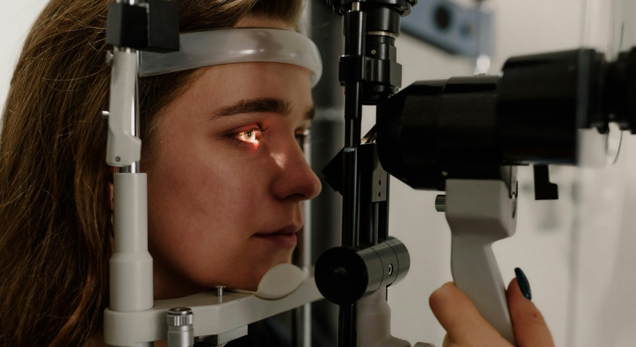 Woman undergoing an eye examination using a slit lamp biomicroscope.