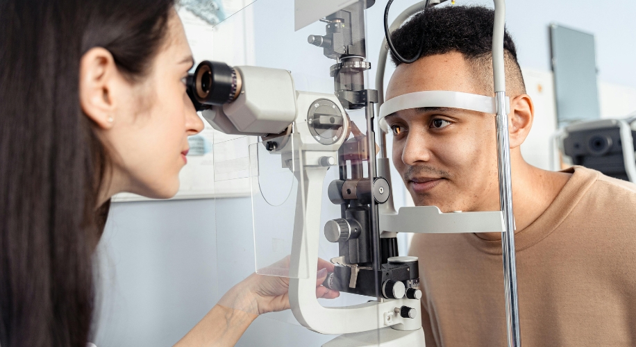 Optometrist examining a patient&#039;s eyes with a slit lamp biomicroscope.