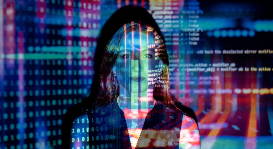 Woman with long hair standing, overlaid with multicolored programming code and digital graphics.