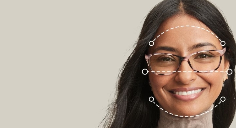 Woman wearing pink glasses with face measurement markers.