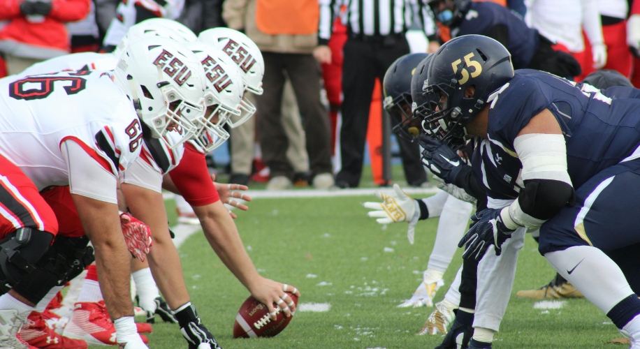 Football players from opposing teams lining up at the line of scrimmage. ESU helmets on the left.