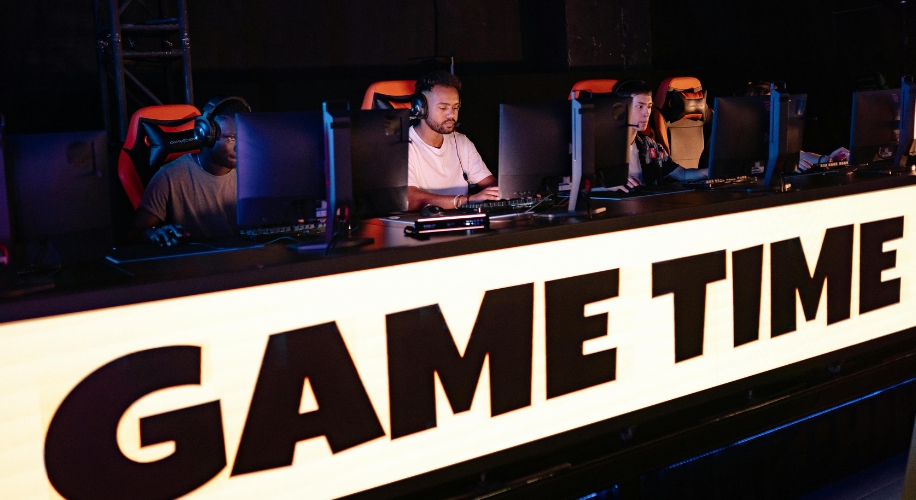 Gamers at computer stations, illuminated sign in front reads &quot;GAME TIME&quot;.