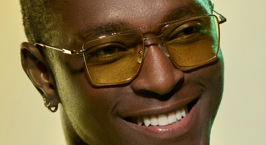 Man wearing glasses with gold frames and yellow-tinted lenses, smiling.