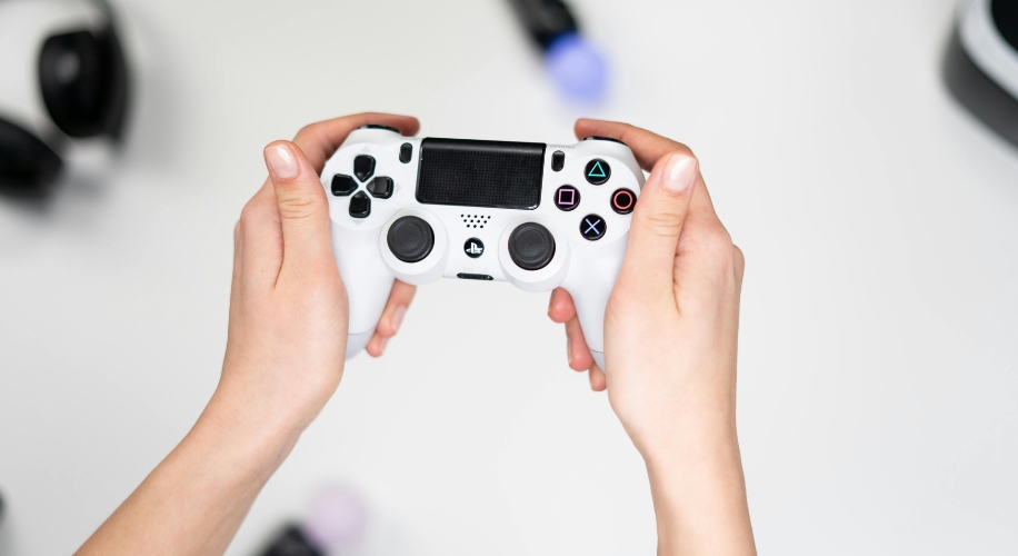 Hands holding a white gaming controller with various buttons and joysticks.