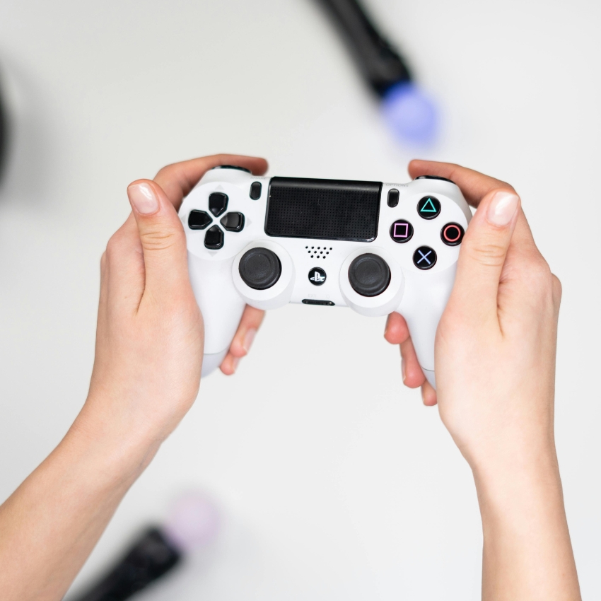 Hands holding a white PlayStation game controller.