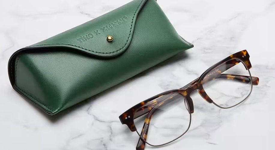 Green leather glasses case with &quot;TIMO X XABANIP&quot; text and tortoiseshell glasses on a marble surface.