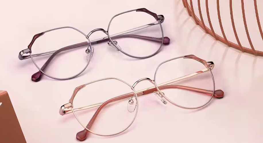 Two pairs of modern, rimmed eyeglasses with transparent lenses; one in light pink and the other in metallic gray.