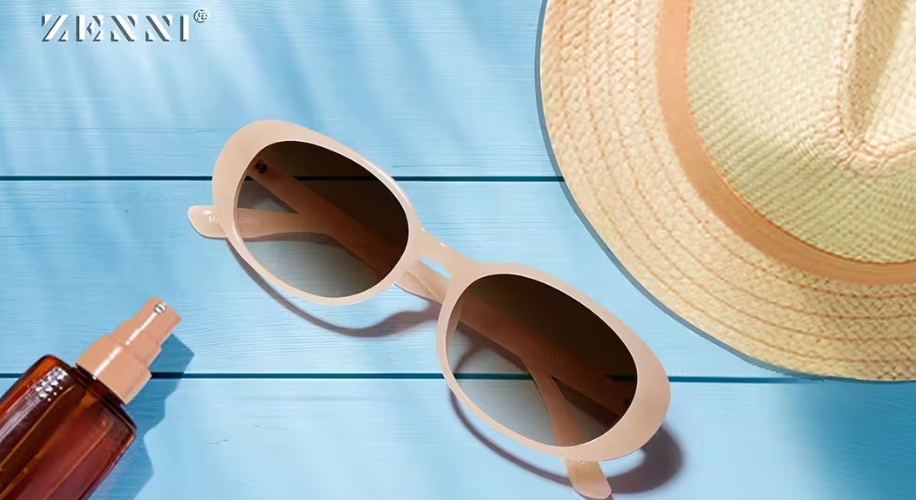 Zenni sunglasses next to sunhat and sunscreen on blue wooden surface.