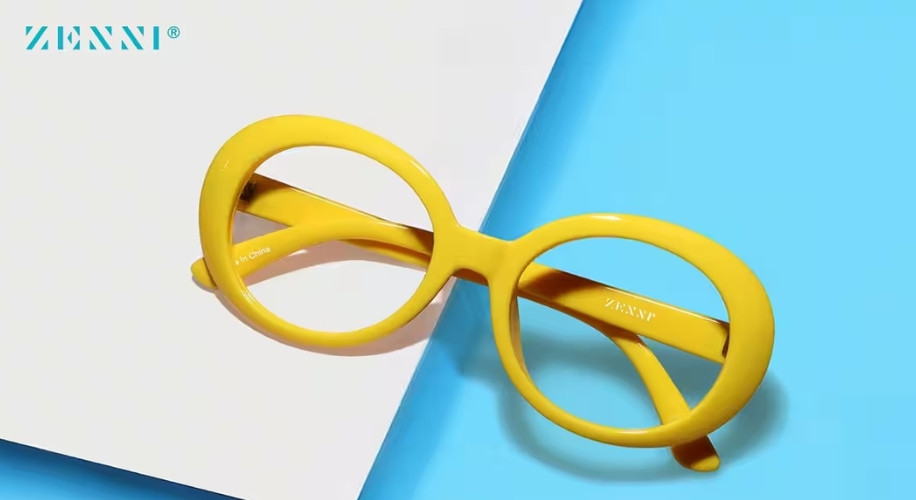 Yellow oval glasses with &quot;Zenni&quot; logo on a blue and white background. Text: &quot;ZENNI®&quot;.