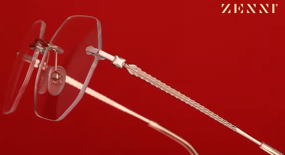 Zenni glasses with rimless design and intricate, textured silver temples against a red background.