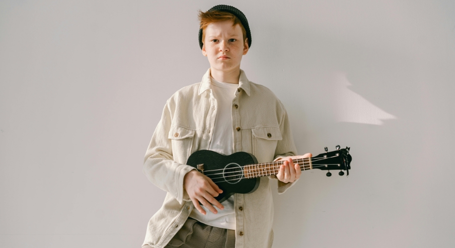 A person holding a black ukulele.