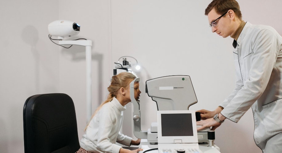 Optometry equipment used for an eye exam on a young patient by an eye care professional.