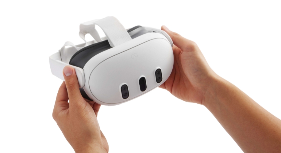 Person holding a white VR headset with three front cameras and adjustable head strap.